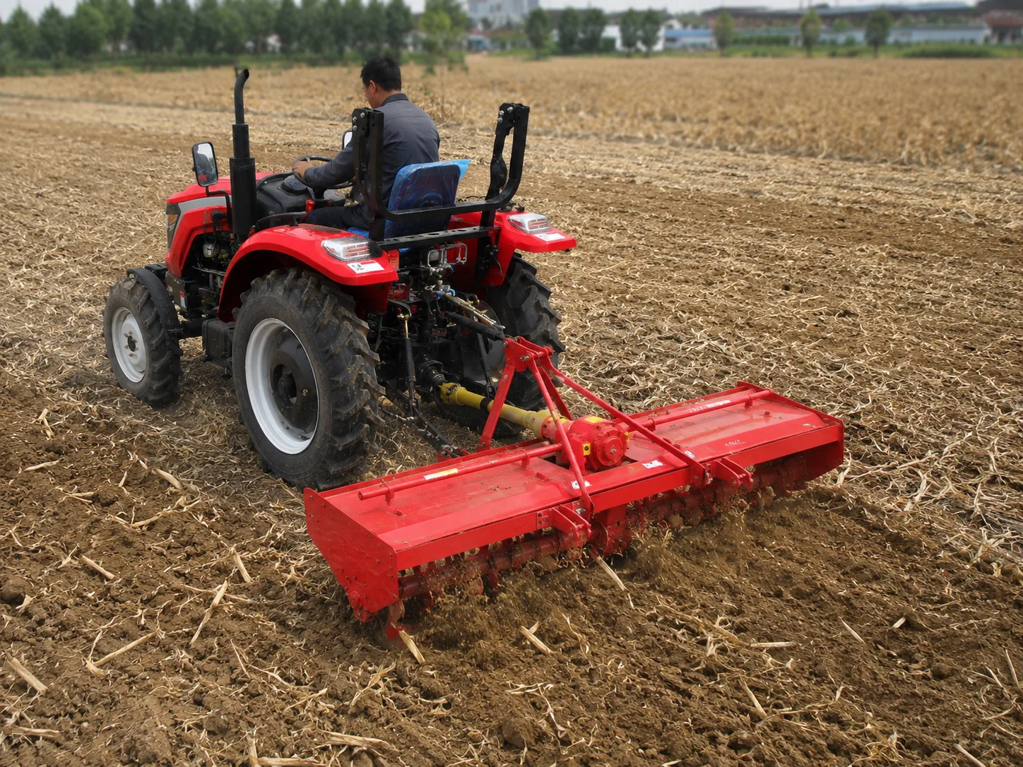 Fresadora rotativa montada en un tractor que labra el suelo y los residuos de cultivo en el campo
